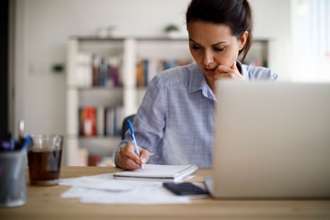 a female writing on a notebook at home